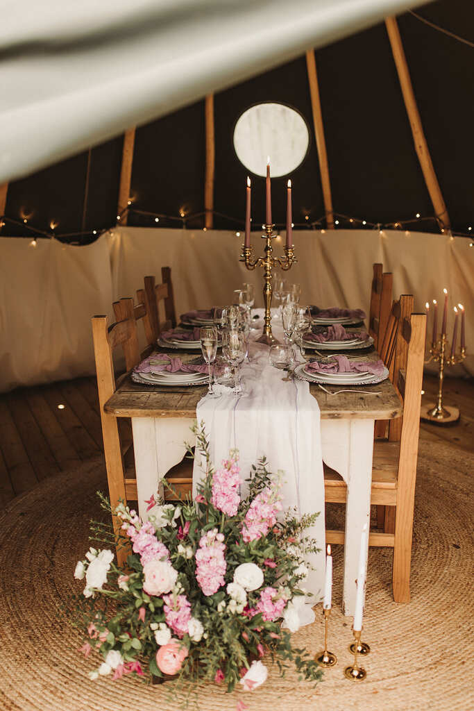 mesa rústica com tecido e candelabros e flores em tenda de tecidos