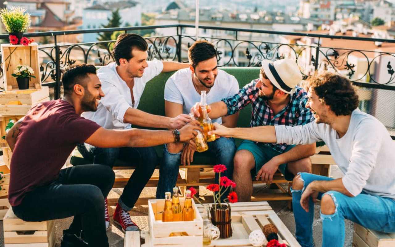 noivo com quatro amigos brindando com garrafas de cerveja em despedida de solteiro