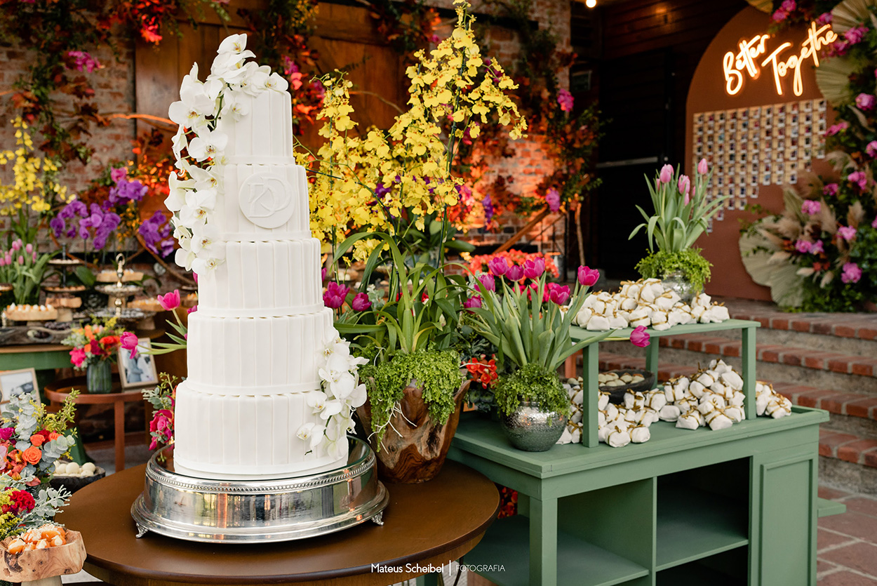 mesa com bolo de casamento branco clássico com 5 andares e orquídeas