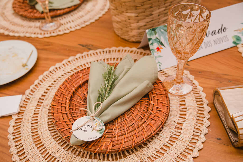 mesa posta com sousplat rústico e guardanapo verde com ramo de alecrim