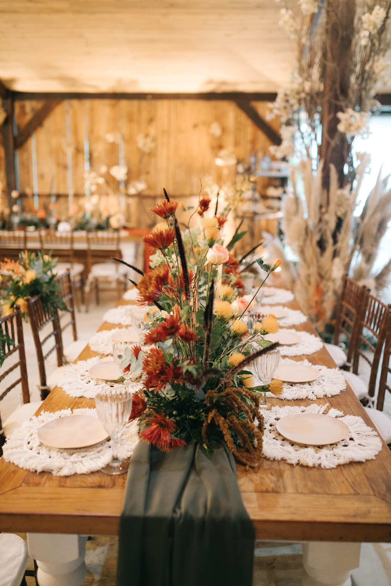 mesa posta com flores no centro e sousplat de crochê dentro de salão rústico