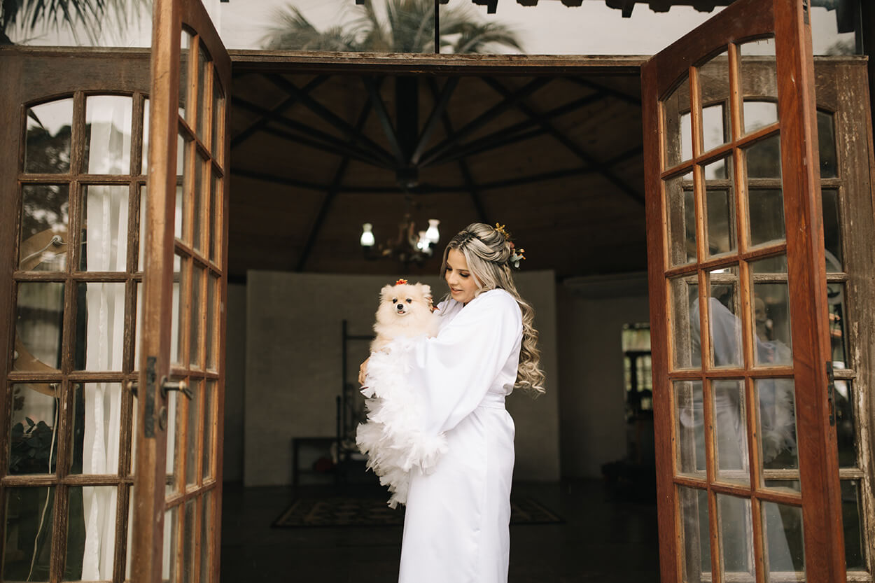 noiva com robe branco carregando no colo cachorro lulu da pomerania