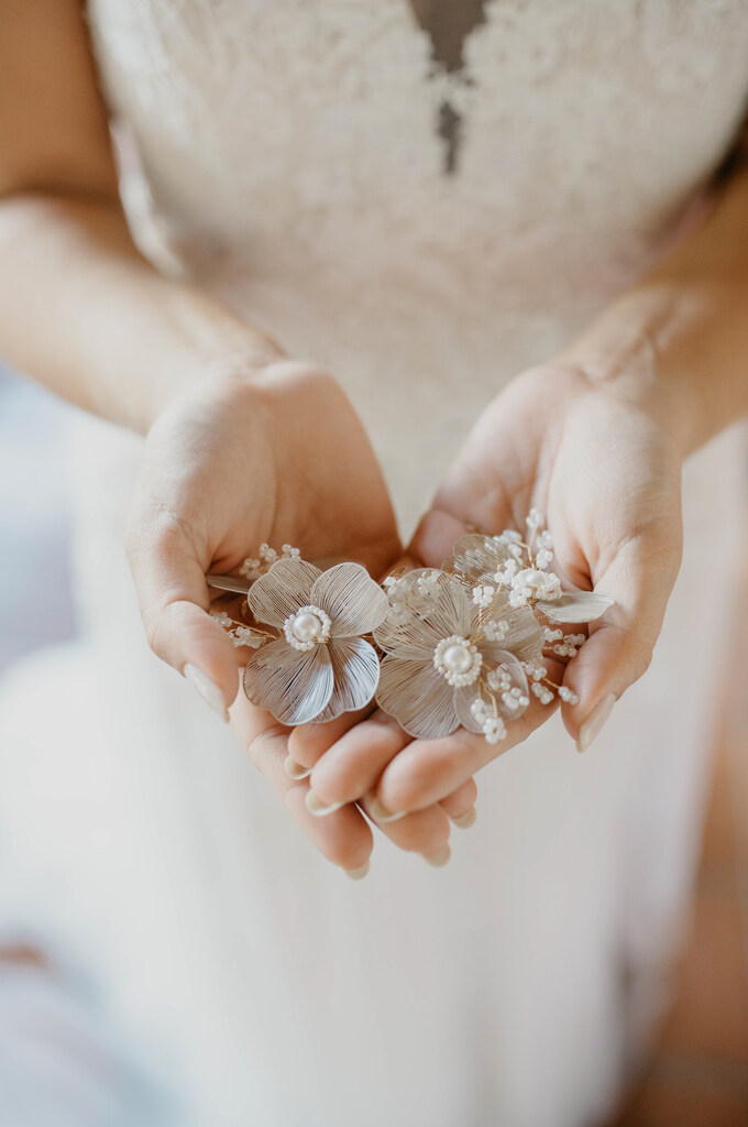 mulher com vestido de noiva segurando grinalda em formato de flores brancas nas mãos