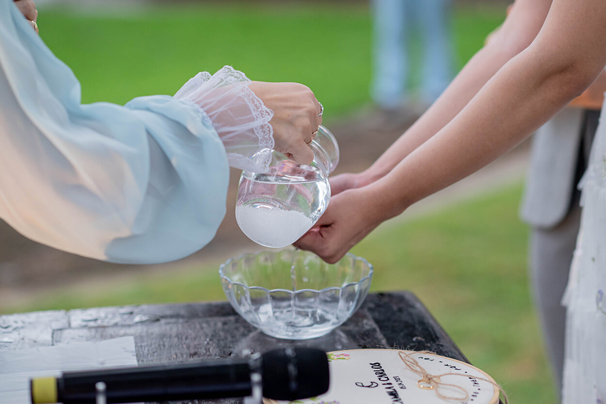 mulher derramando água as mãos da noiva durante a cerimonia 