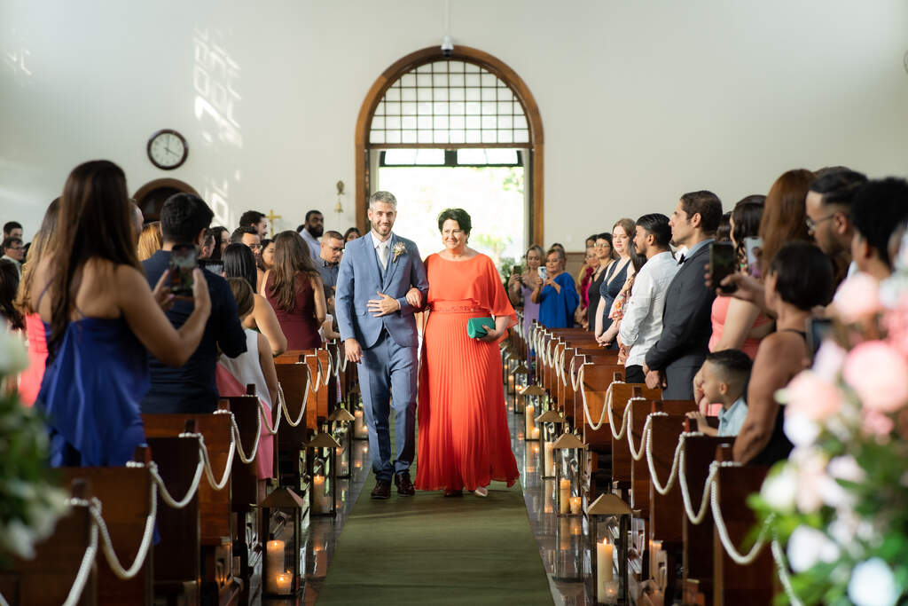 entrada do noivo com tenro azul ao lado da mãe com vestido laranja 