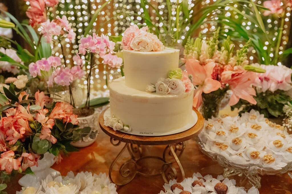 mesa de madeira com bolo de casamento branco de dois andares com flores