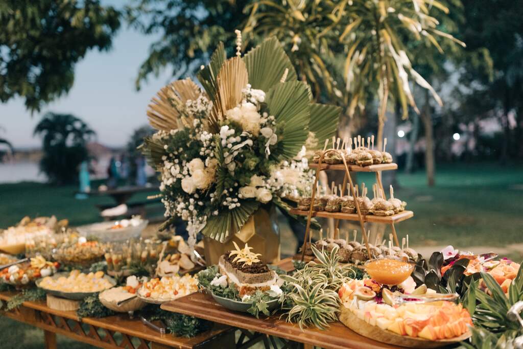 mesas de madeira com vasos com flores e pantas ao lado de tábuas com petiscos