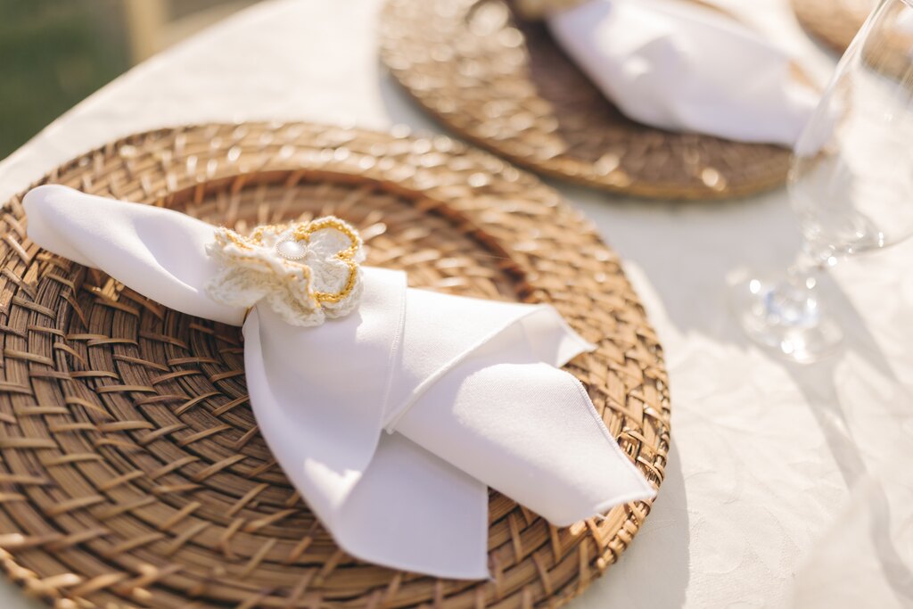 mesa posta com sousplat com guardanapo branco com detalhe de flor de crochê