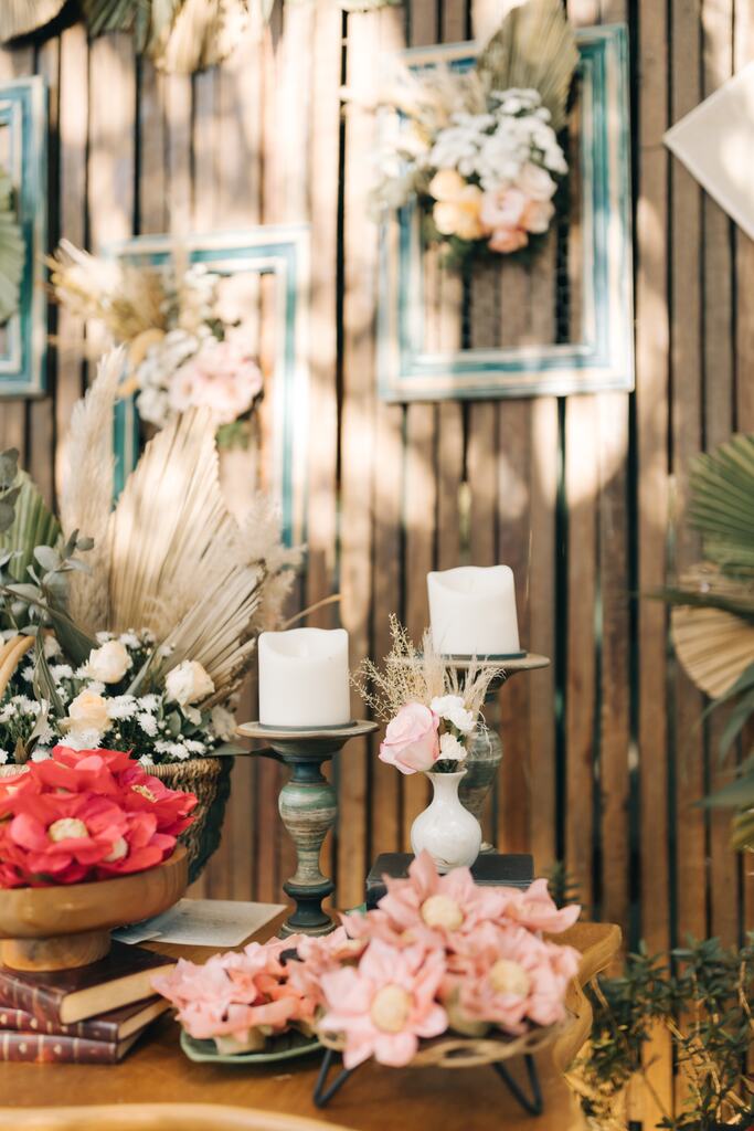 castiçais rústicos com velas brancas ao lado de bandejas com doces de casamento em forminhas em formato de flores