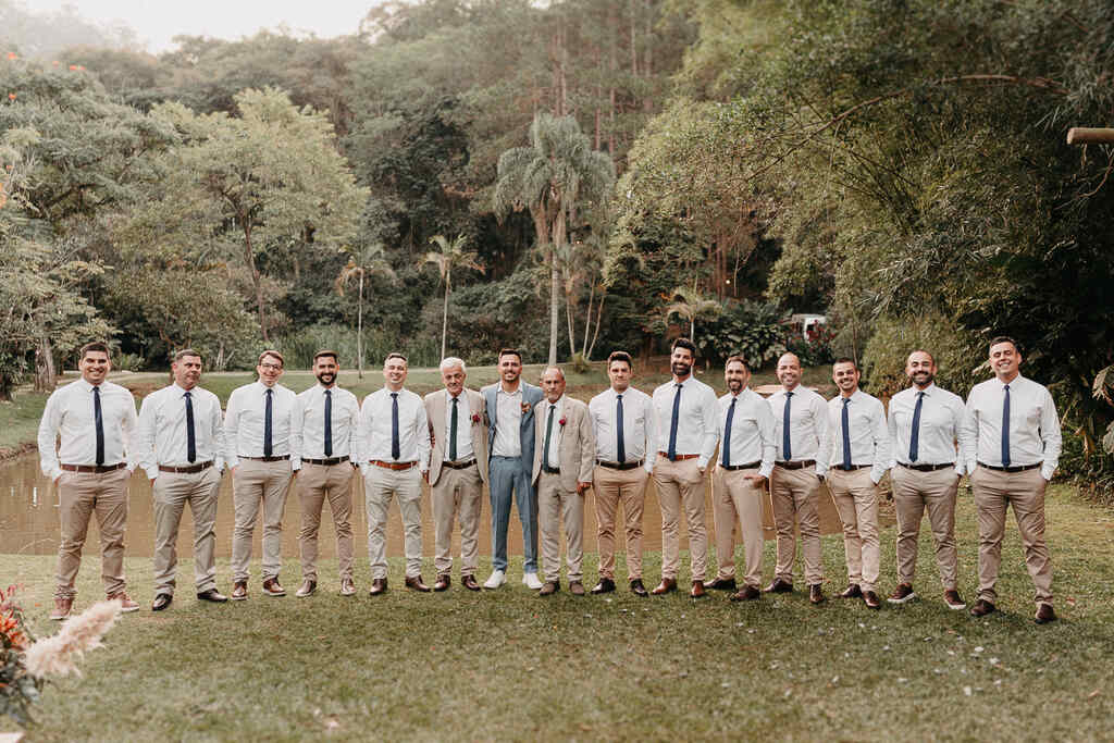 noivo com terno azul ao lado dos padrinhos com calças bege com camisa branca com gravata verde