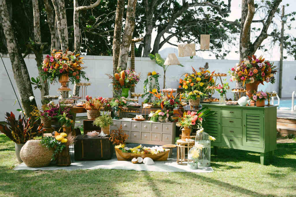 mesas brancas e verdes com vasos de flores e bandejas de doces ao ar livre