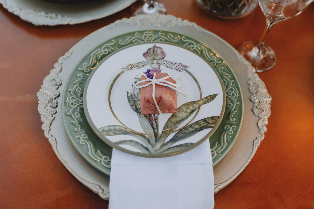 mesa posta com sousplat rustico bege com prato com estampa de flores e bem casado em cima