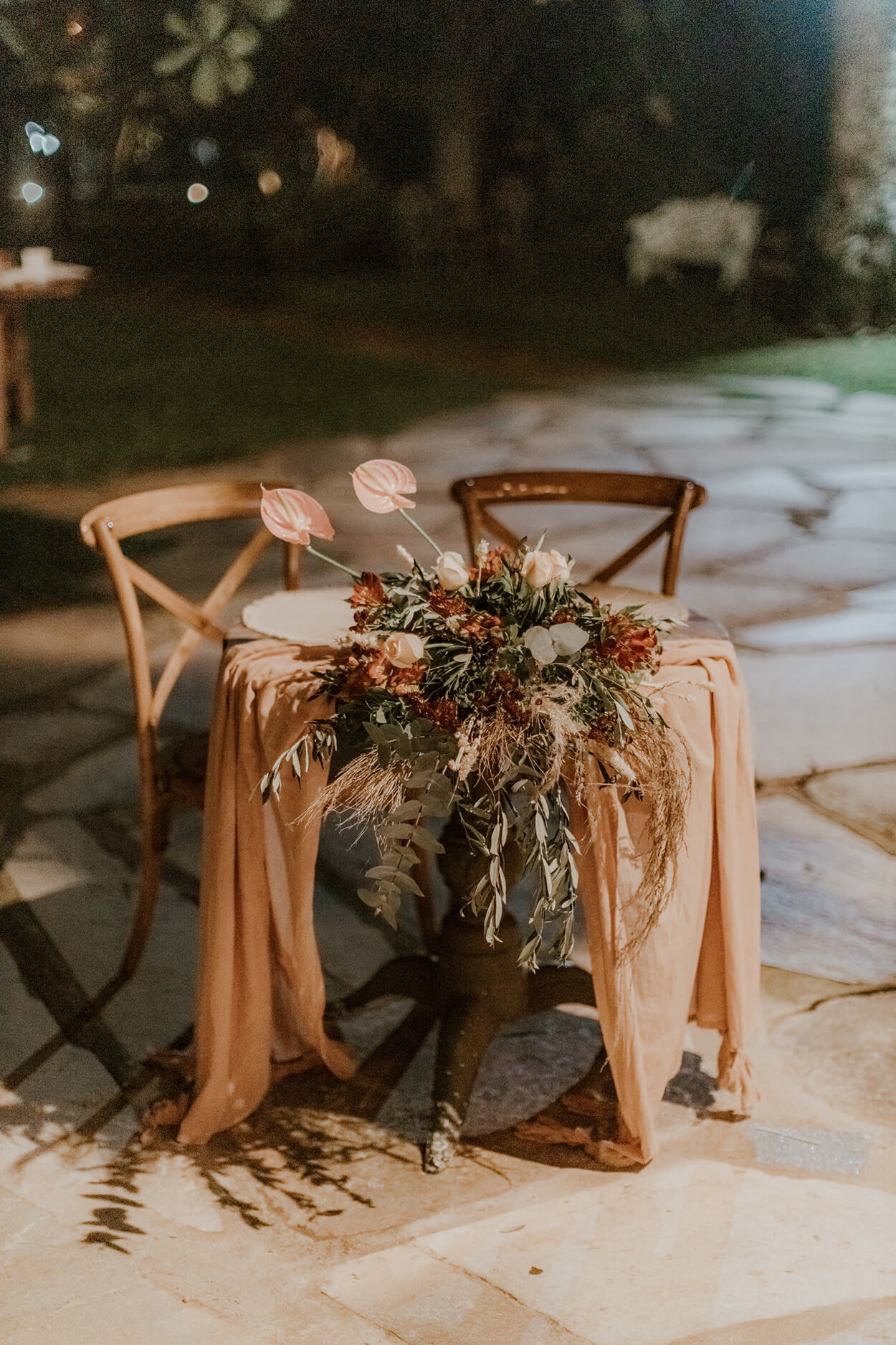mesa dos noivos redonda de madeira com tecido terracota com arranjo de flores rosas e terracota