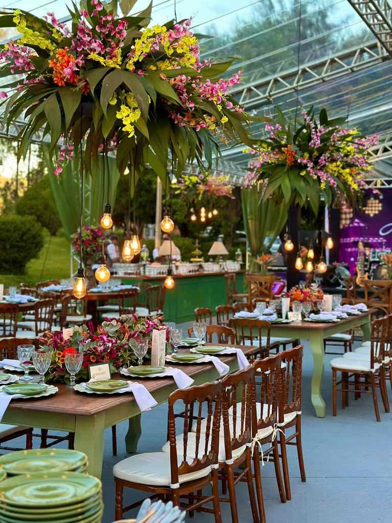 salão com mesas verdes postas com flores no ccentro