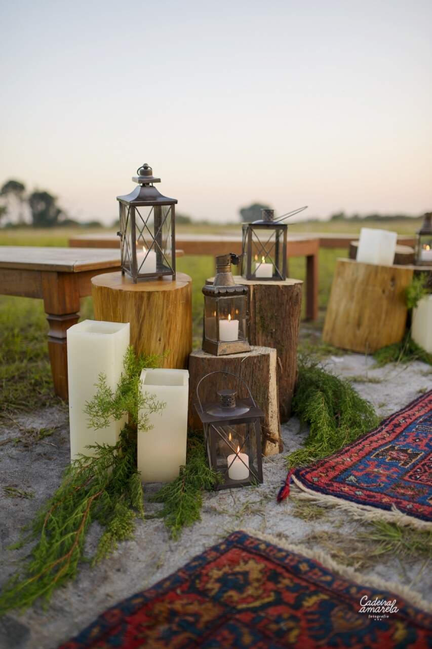 bancos de madeira e toras com candelabro com velas ao ar livre