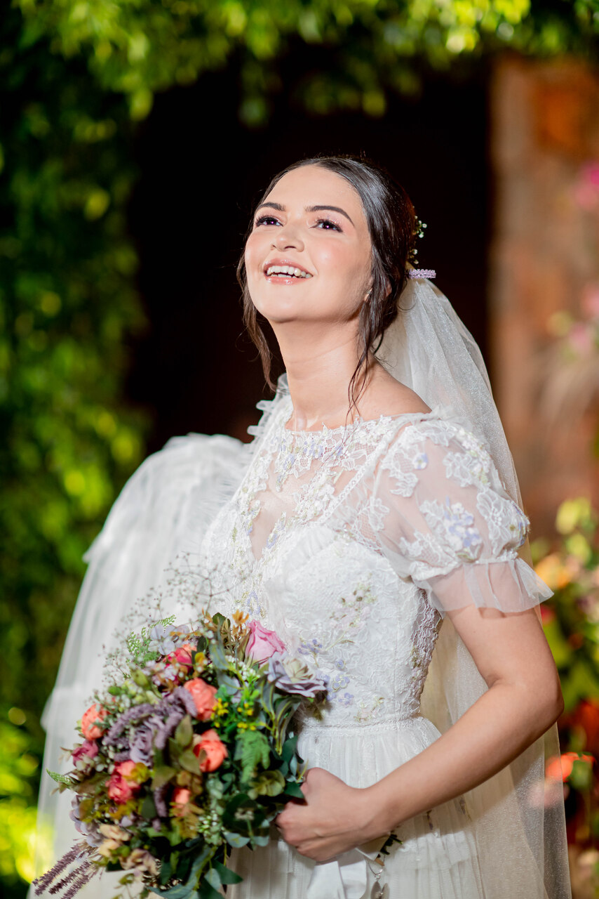 vestido de noiva com manga e segurando um buquÊ colorido