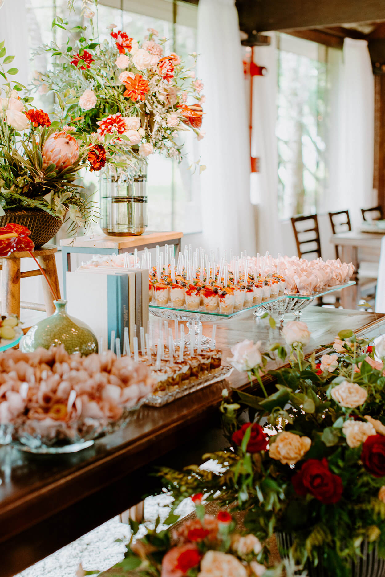 mesa com flores e bandejas com comidas e doces