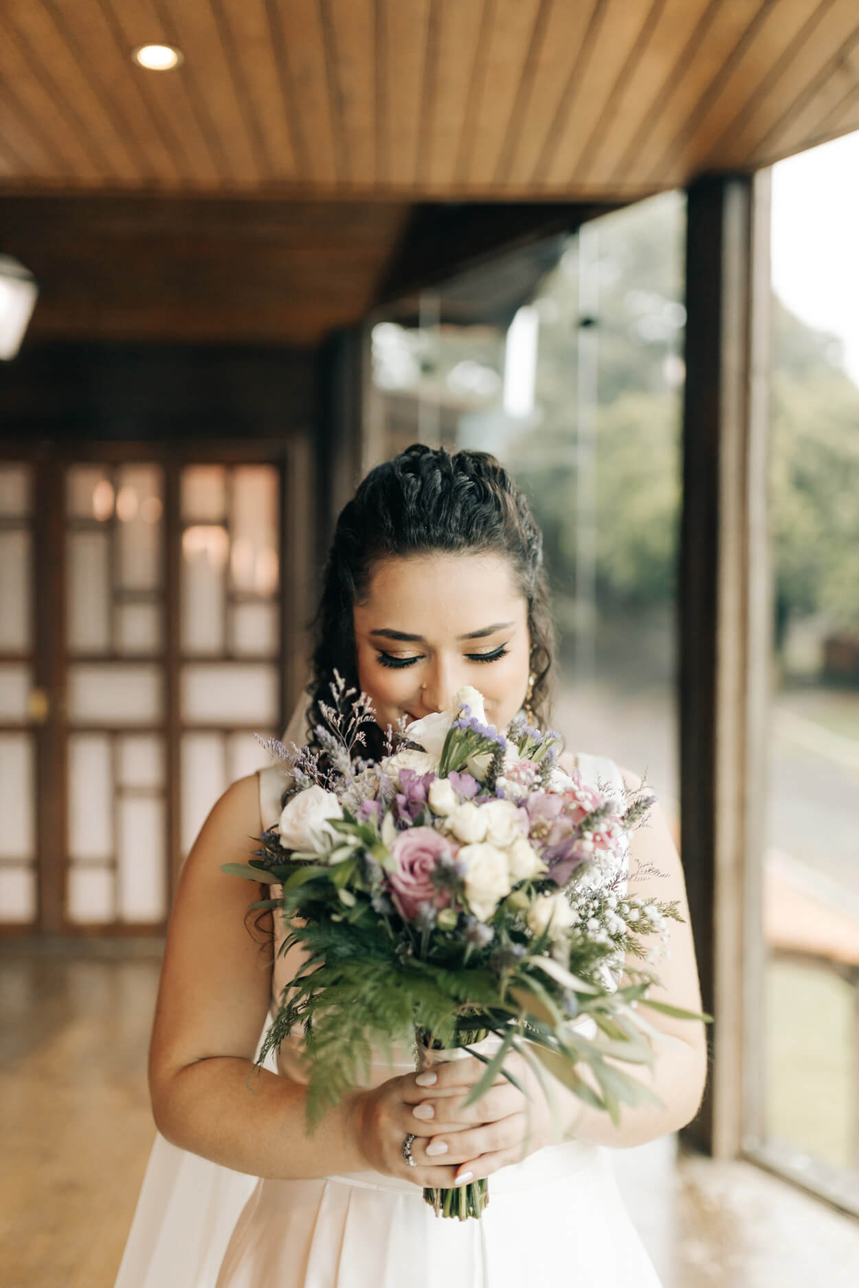 noiva com cabelo cacheado segurando buquÊ com flores lilás