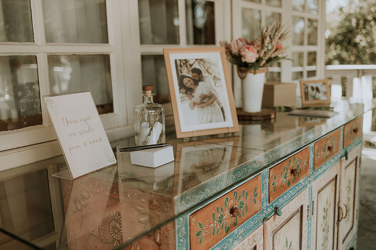 mesa de madeira com tampo de vidro com porta retrato e vasos de flores 