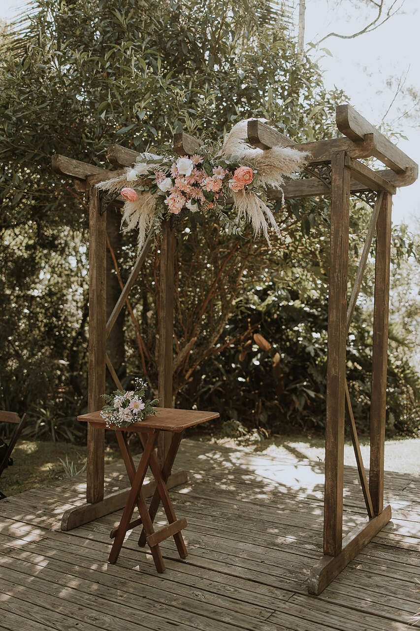 altar de madeira rústico enfeitado com flores rosas e capim dos pampas