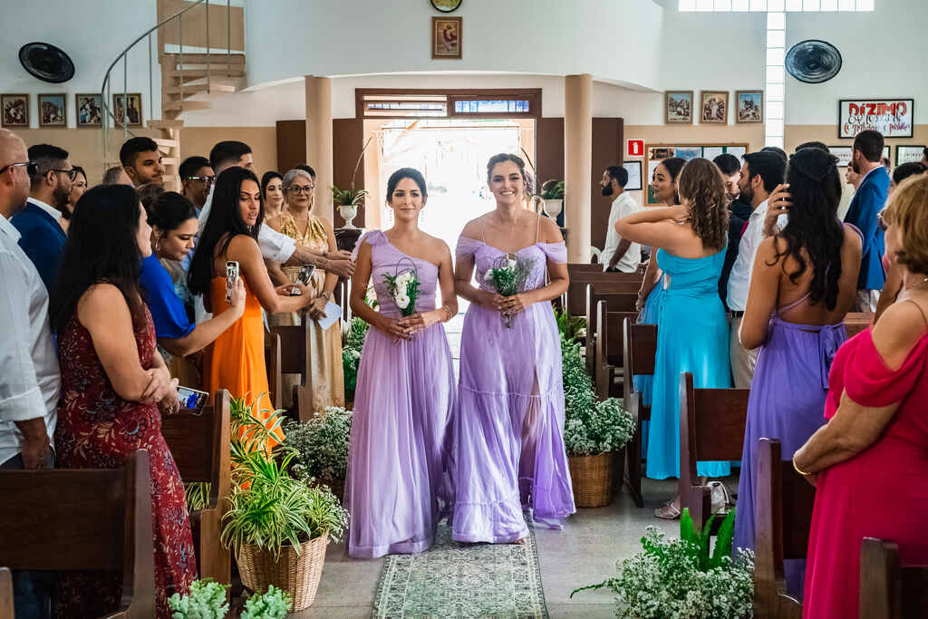 entrada da demoiselles com vestidos longos lilás e segurando buquê com flores brancas