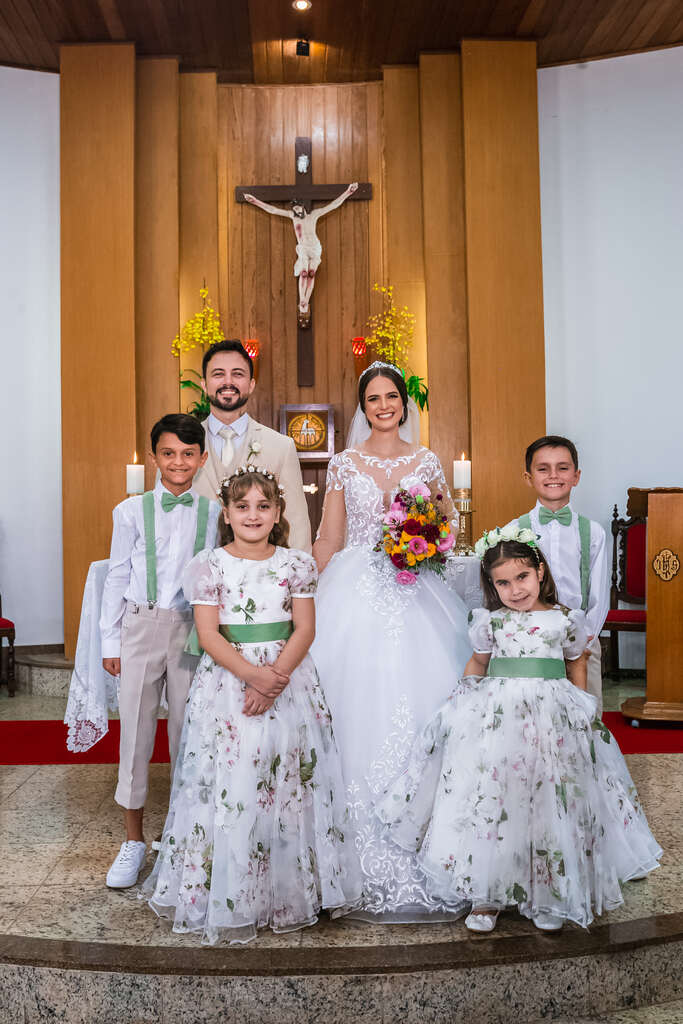 daminhas e pajens na frente dos noivos no altar da igreja