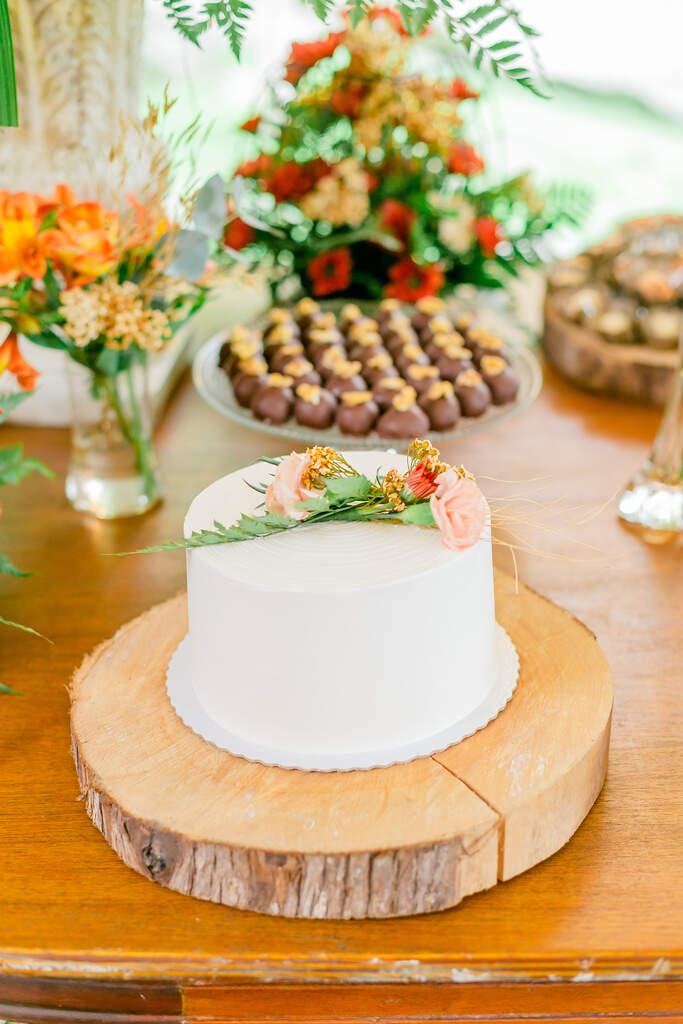 bolo de casamento branco espatulado com flores rosas e laranjas no topo