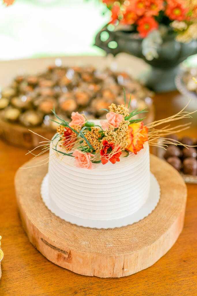 bolo de casamento branco espatulado com flores rosas e laranjas no topo