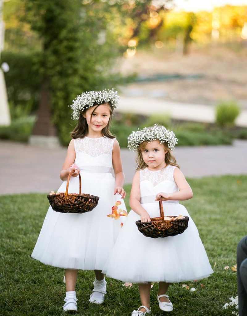 duas floristas de casamento crianças com vestido branco, coroa de flores branca, sapatos brancos e cesta de vime com flores