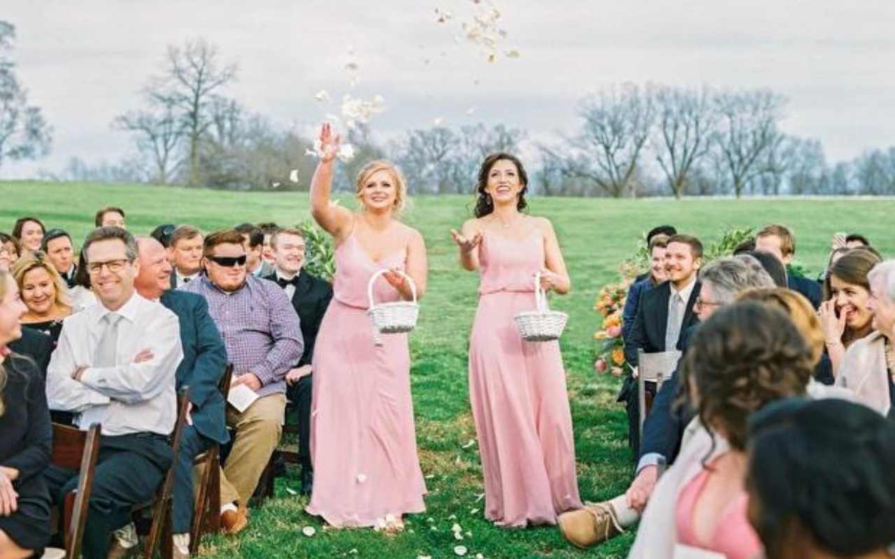 duas floristas de casamento adultas com vestido rosa jogando pétalas brancas no caminho da noiva