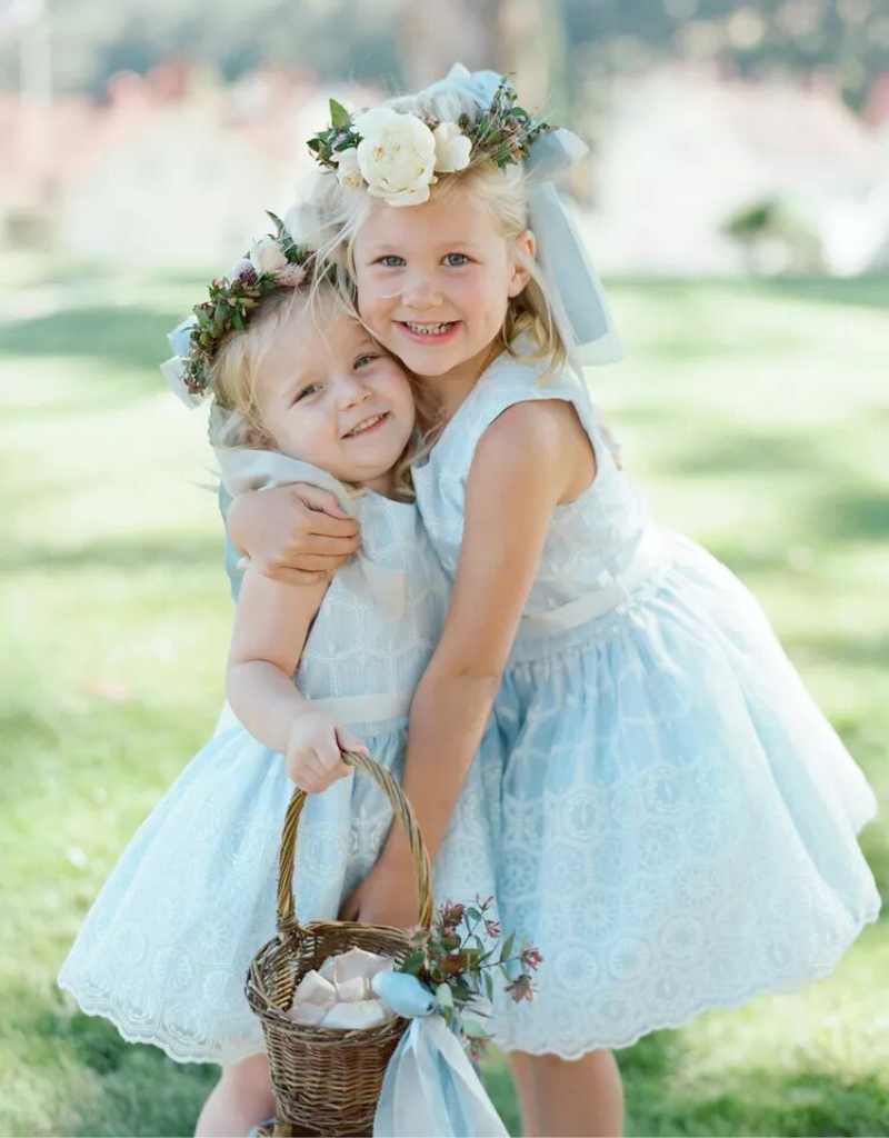 duas floristas de casamento se abraçando com vestidos azuis e coroa de flores