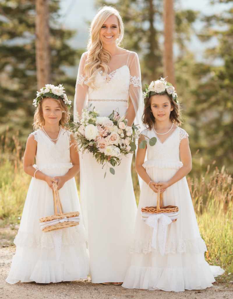 noiva loira ao lado de duas floristas de casamento crianças com vestidos brancos