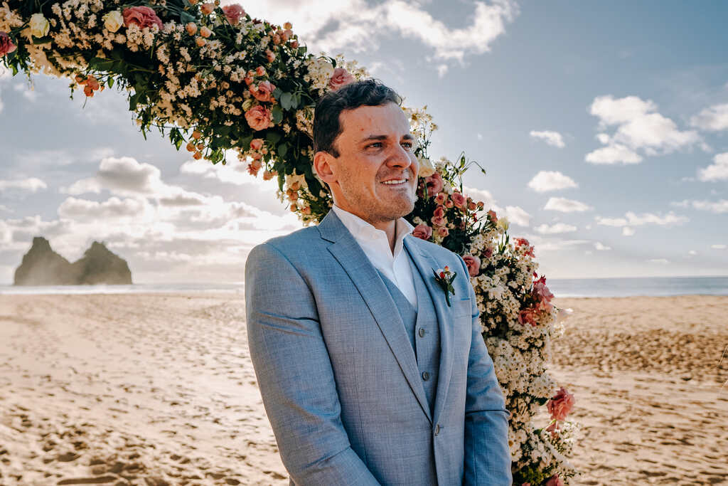 noivo emocionado no altar com flores para casamento na praia