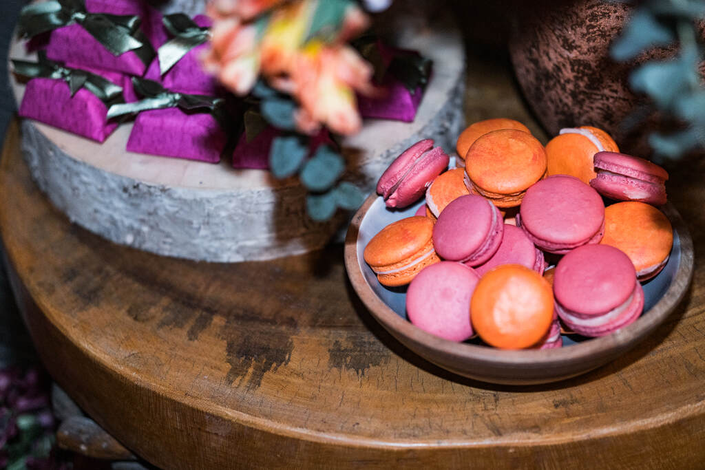 bandeja de madeira sobre a mesa com macarron laranja e cor de rosa 