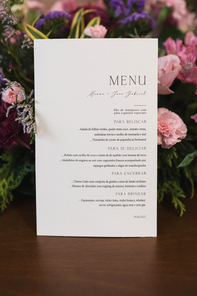 menu de casamento branco em frente a arranjo com flores
