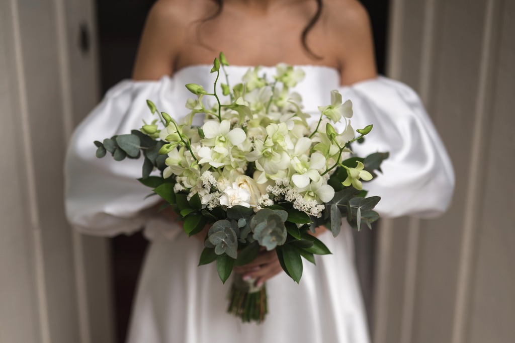 noiva com vestido minimalista com manga bufante segurando buquÊ redondo com flores brancas 