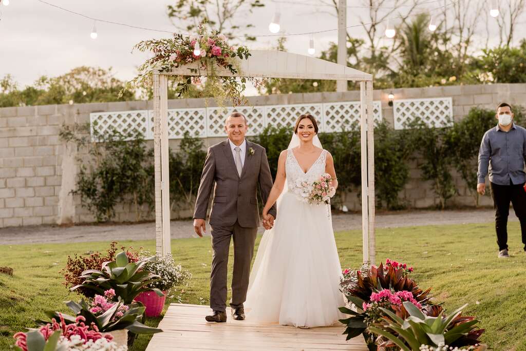 entrada da noiva com buquê rosa e branco ao lado do pai com tenro cinza