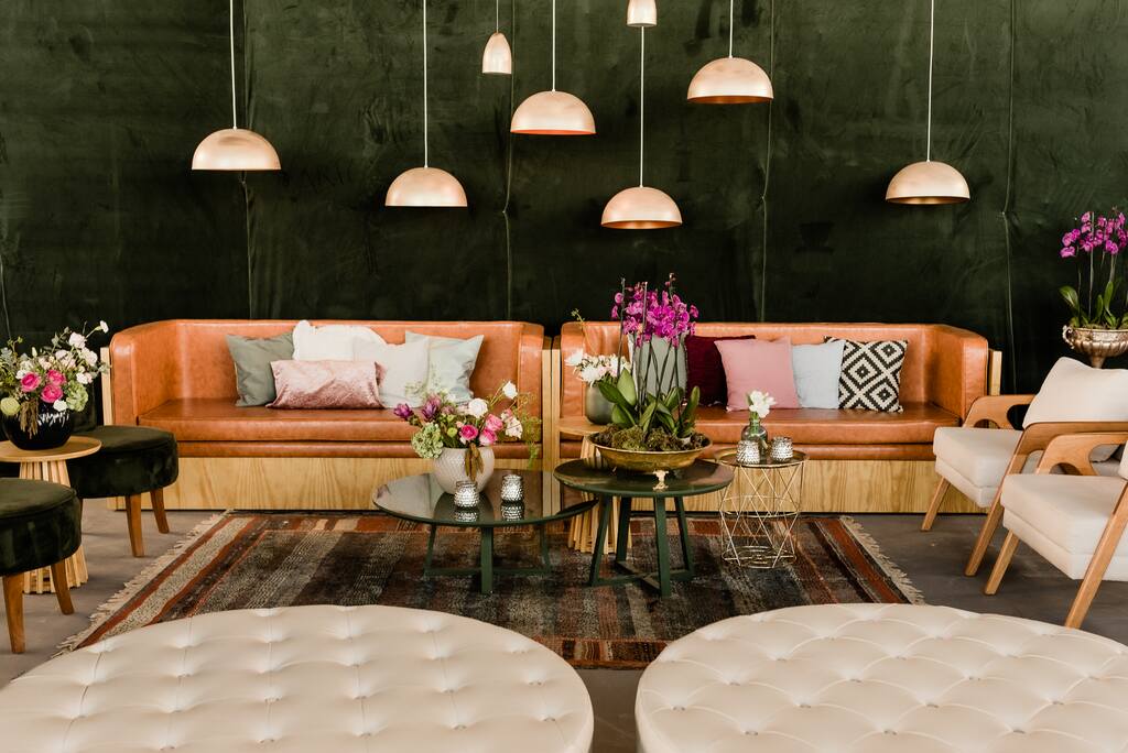 lounge no salão com dois sofás marrons com almofadas coloridas e luminarias modernas pendentes