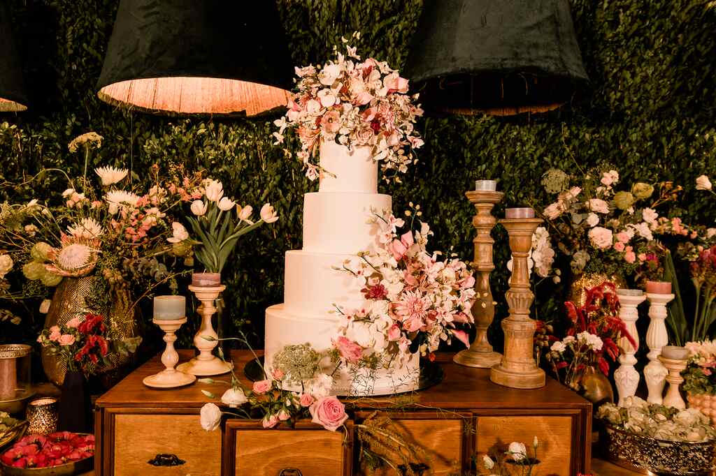 mesa com bolo de casamento com quatro andares com tpo de flores brancas e cor de rosa
