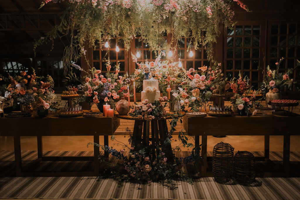 mesa com bolo de casamento com flores e luminarias pendentes