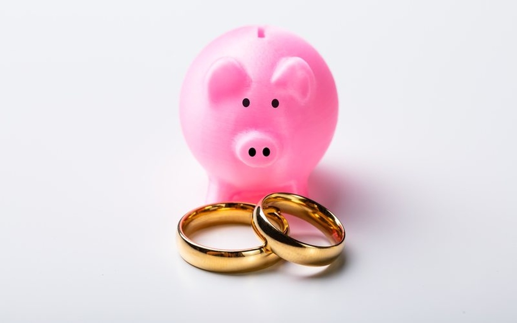 porquinho de plástico cor de rosa e alianças douradas na frente representando como arrecadar dinheiro para casamento