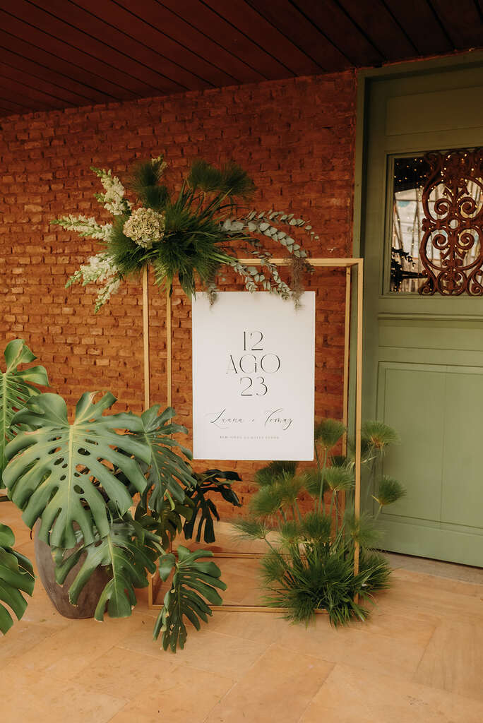 placa de bem-vindos branca e vasos de plantas ao lado