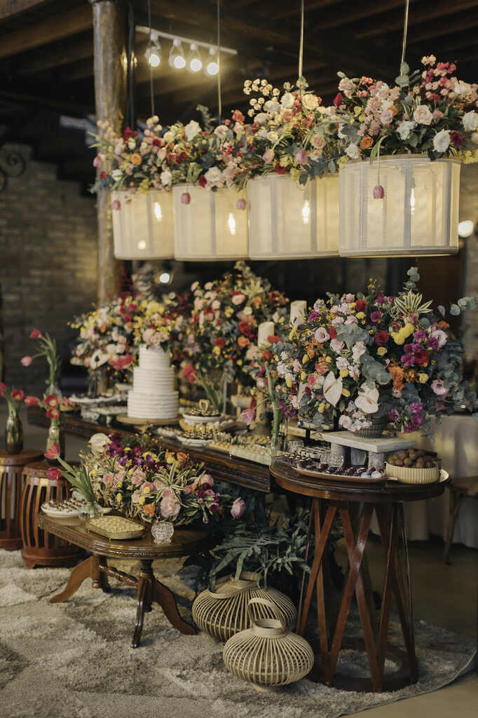 mesa rústica com bolo de casamento branco com arranjos de flores coloridas