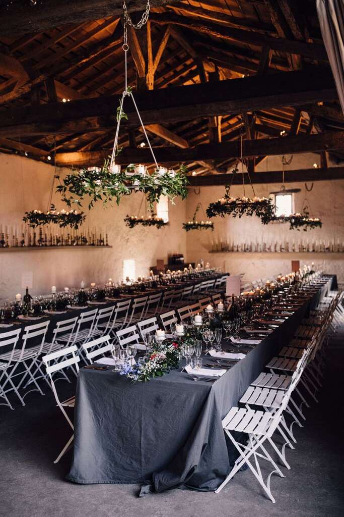 salão rústico com mesas comunitárias com toalha preta e centro e dmesa decorada com flores e velas