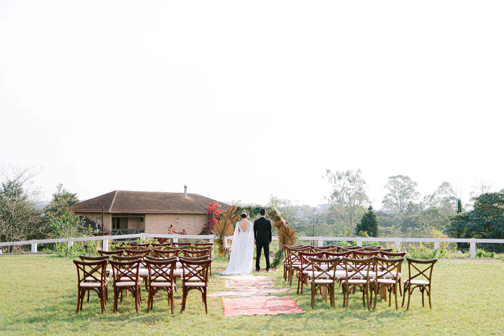 noivos no altar redondo com capim dos pampas no campo com cadeiras e madeira clássicas 