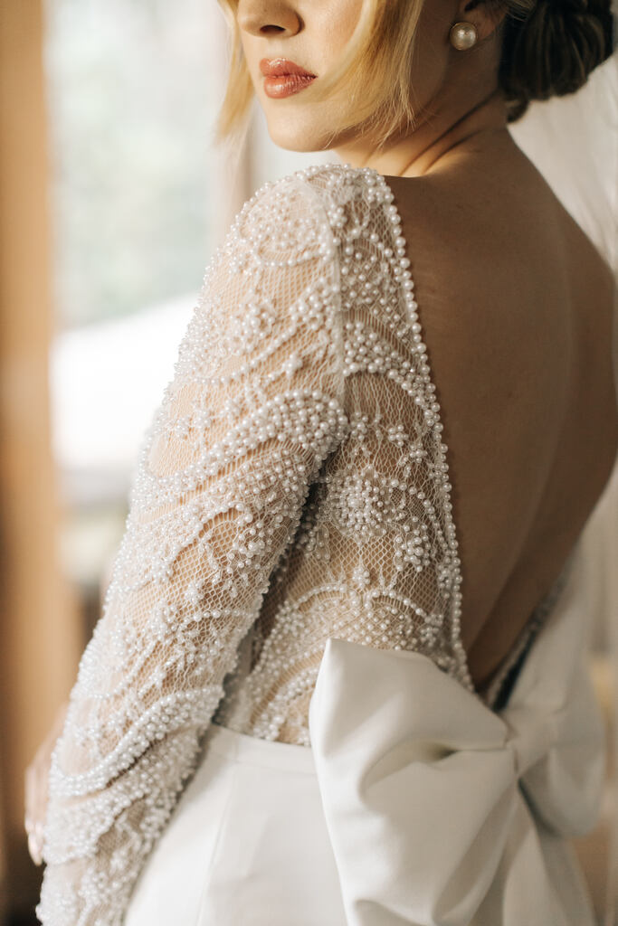 vestido de noiva com manga longa com bordado com pérolas e decote em v nas costas com laço