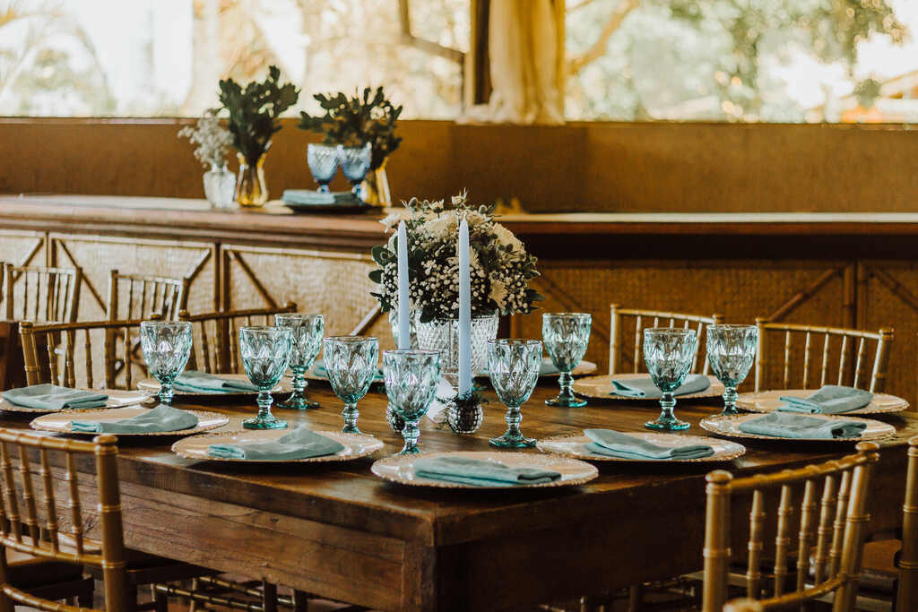 mesa de madeira quadrada posta com com guardanpos taças e velas azul serenity