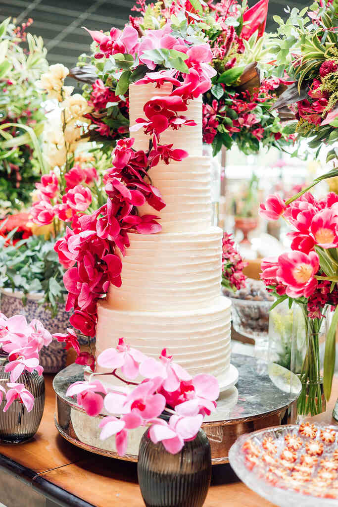 bolo de casamento branco com quatro andares com orquideas na cor fucsia no topo