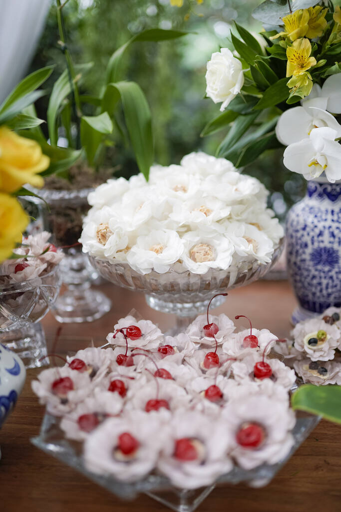 bandeja de vidro com doces de casamento com forminhas de flores brancas