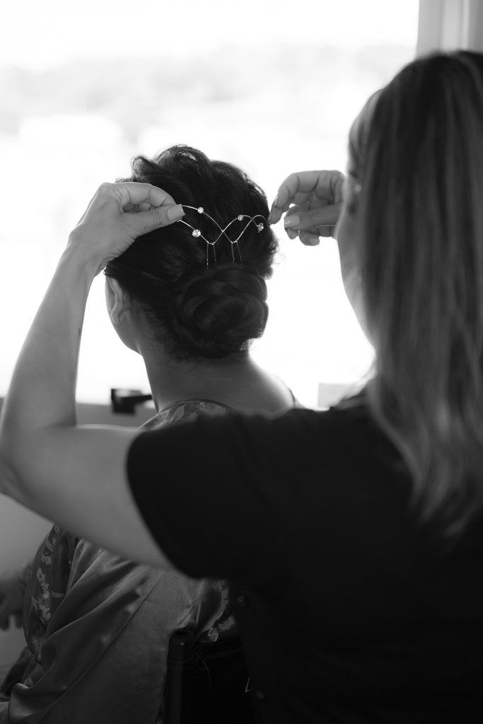 mulher ajustando grinalda no cabelo da noiva